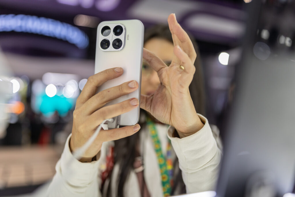 Mulher fotografa a câmera traseira de um smartphone exposto na Eletrolar Show