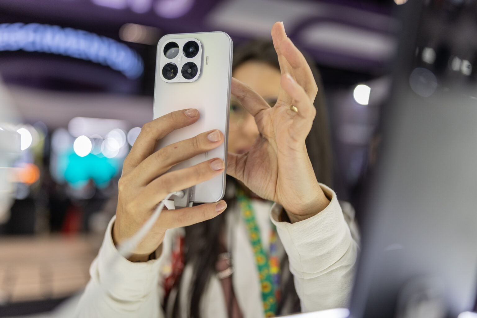 Mulher fotografa a câmera traseira de um smartphone exposto na Eletrolar Show